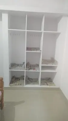 a closet with white shelves and books in it at Aswathy Bhavan in Vadakkāncheri