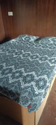 a bed with a blue quilt on top of it at Bison valley in Ooty