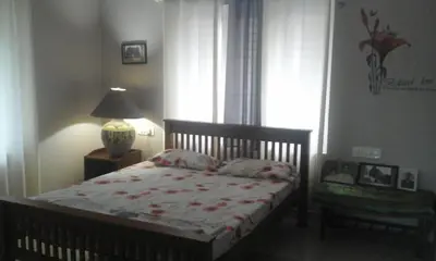 a bedroom with a bed and a lamp and a window at Parthipuram in Thottada
