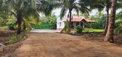a dirt road in front of a house with palm trees at LBS Farms in Coimbatore