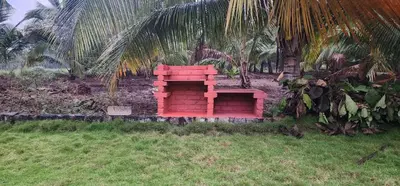 a red couch sitting in the grass next to a palm tree at LBS Farms in Coimbatore