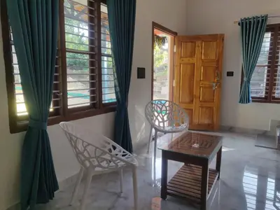 a room with two chairs and a table and a door at Golden Valley Abode in Siddapur