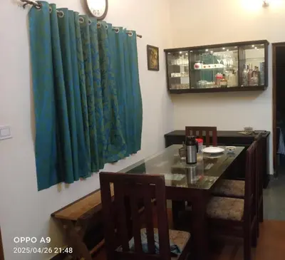 a dining room with a table and a blue curtain at Puthooram Veedu in Kannur