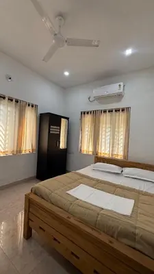 a bedroom with a large bed and two windows at Moksha Farm Stay in Edappāl