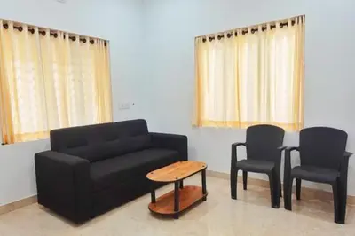 a living room with a couch and two chairs and a table at Moksha Farm Stay in Edappāl