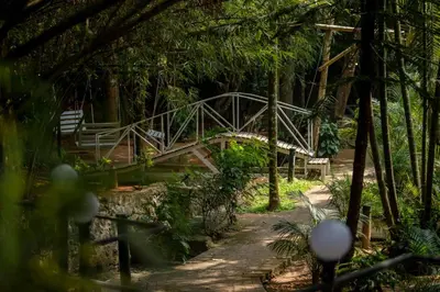 a wooden bridge in a park with a bench at Lakkidi village resort wayanad in Vythiri