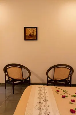 a room with two chairs and a table with flowers on it at 1st Miracle By Mirth, Mythadi , Coorg in Ammatti