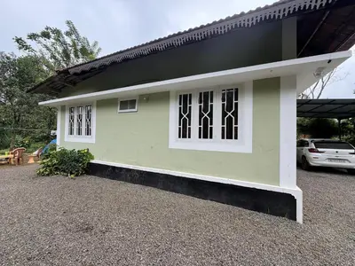 a small green and white house with a car parked at Riverside Homestay Mankulam in Viripara