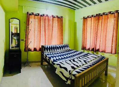 a bed in a room with green walls and windows at Riverside Homestay Mankulam in Viripara