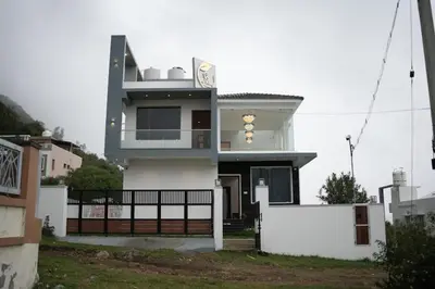 a white house with a fence in front of it at Vaj N Sat Villas in Kodaikānāl