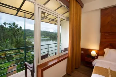 a bedroom with a balcony with a view of a river at Karlad Lake Resort in Wayanad
