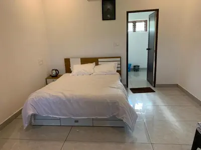 a bedroom with a large bed with white sheets and pillows at Elysian in Mananthavady