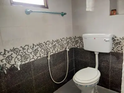 a bathroom with a toilet with a hose at Nira Homestay in Kodaikānāl