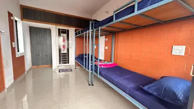 a room with three bunk beds in a brick wall at Campside Stays in Nāganahalli
