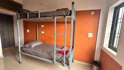 two bunk beds in a room with an orange wall at Campside Stays in Nāganahalli