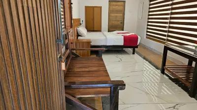 a room with a bed and a door with a bench at Vayuvana Heritage Organic Farm Resort in Panamaram