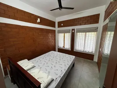 a bedroom with a bed and a brick wall at 3 bhk Premium home Stay at Ernakulam Aluva Perfect for Family and Long stay in Alwaye
