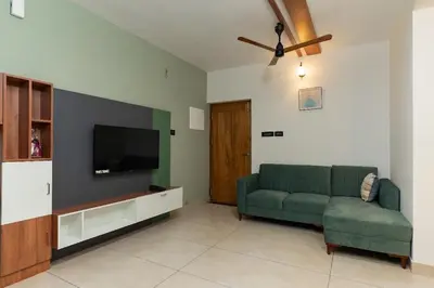 a living room with a green couch and a flat screen tv at Couple friendly apartment in Kozhikode