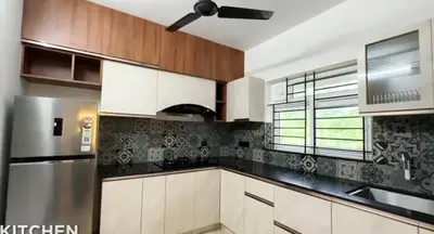 a kitchen with white cabinets and a stainless steel refrigerator at Couple friendly apartment in Kozhikode