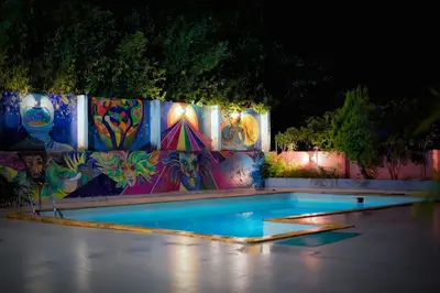 a swimming pool at night with a colorful wall at Girassol Serviced Villa in Vythiri