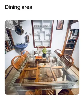 a dining area with a glass table and chairs at NirvanaStays-Blooms in Tariyod