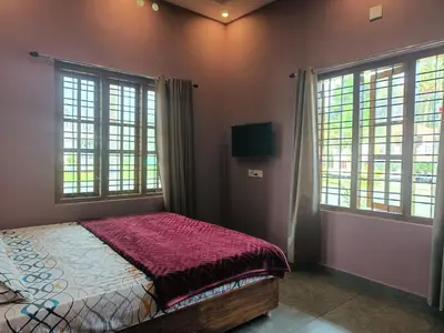 a bedroom with a bed and two large windows at Eden Spot in Marayoor