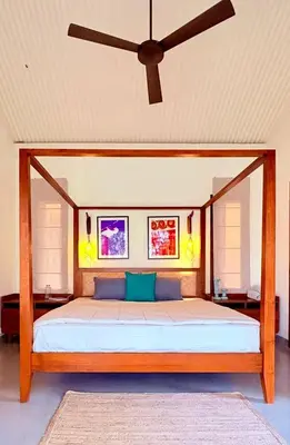 a bedroom with a large bed with a ceiling fan at Chandra - Journey back to you in Honganūr