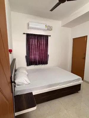 a bed in a room with a white mattress and a window at Krish homes in Coimbatore