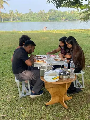 a group of people sitting at a table eating food at Some where Else Musiris Heritage in Parūr