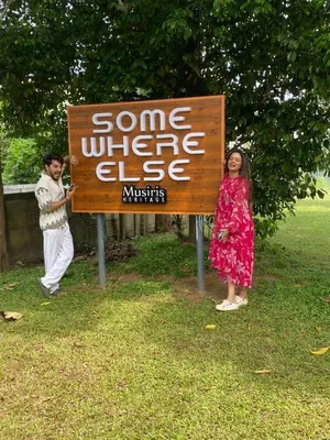 a man and a woman standing next to a sign at Some where Else Musiris Heritage in Parūr