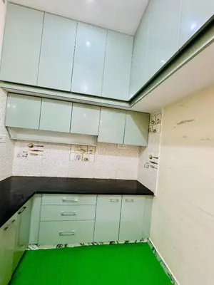 an empty room with white cabinets and a green floor at Flats in CITY Centre Next to Nexus Mall, 1km from bus stand in Mysore