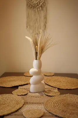 a white vase with a feather in it on a table at Nilgiri Breeze Apartment in Pīlamedu
