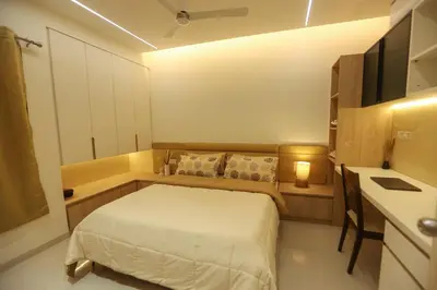 a small bedroom with a bed and a desk at Nilgiri Breeze Apartment in Pīlamedu