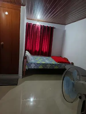 a bedroom with a bed and a window with a fan at Ananya Homestay in Napoklu