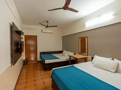 a hotel room with two beds and a ceiling fan at Royal Residency in Coimbatore