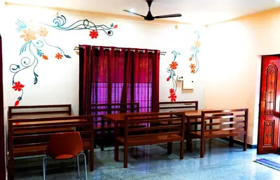 a dining room with tables and chairs and a painting on the wall at BGF Residency - Cottage in Coimbatore