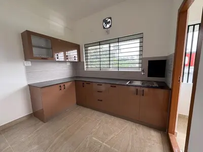 a kitchen with wooden cabinets and a large window at Twilight Residency in Kizhake Chālakudi