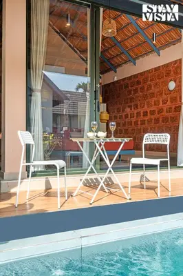 a patio with a table and chairs next to a pool at StayVista at The Sattva Grove with Pool, Views in Wayanad