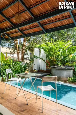 a patio with a table and chairs next to a pool at StayVista at The Sattva Grove with Pool, Views in Wayanad