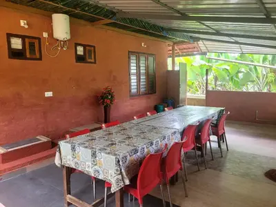a long table and red chairs in a room at Dream Acres Mudhouse in Vallikavungal