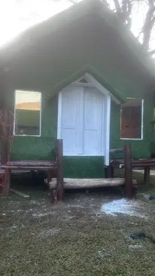 a green house with a white door and two windows at Bethel resorts in Kanthalloor