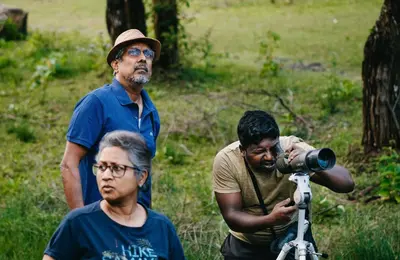 a group of three men standing next to a camera at Jungle Hut Resort in Masinagudi