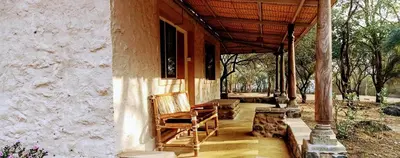 a porch of a house with chairs on it at Jungle Hut Resort in Masinagudi