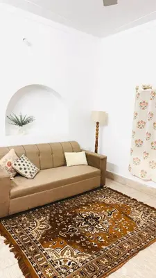 a brown couch in a living room with a rug at Nele Mane in Mysore