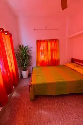 a bedroom with a bed with orange and red curtains at Nele Mane in Mysore