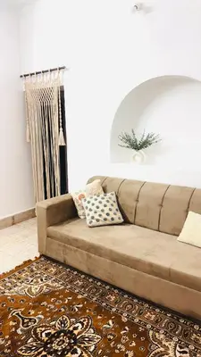 a brown couch in a living room with a rug at Nele Mane in Mysore