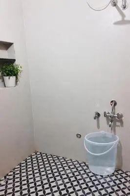 a bathroom with a bucket on a tiled floor at Nele Mane in Mysore