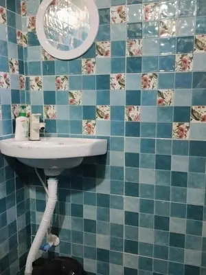 a blue tiled bathroom with a sink and a mirror at Dreams home estate stay coorg in Suntikoppa
