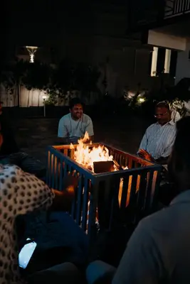 a group of people sitting around a fire at night at Fenna Resort And Spa, coorg in Kushālnagar