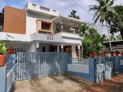 a house with a blue fence in front of it at Kalariyullathil Homestay